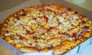 Pyszna pizza hawajska w pudełku, idealna do szybkiego odgrzania w mikrofali.