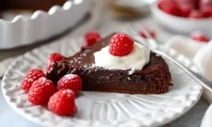 En bit kladdkaka med vispad grädde och hallon, perfekt för ett kladdkaka recept.