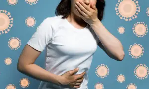 Kobieta z ręką na ustach i brzuchu, czuje się źle z powodu grypy żołądkowej. Wokół niej unoszą się wirusy.