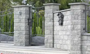 Betonowy słupek z zamontowaną skrzynką na listy i fragmentem metalowej furtki.