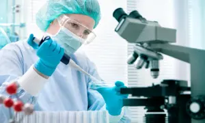 Badacz w rękawiczkach pobiera pipetą płyn z szalki Petriego, obok mikroskop i probówki. Badania naukowe, ige całkowite.