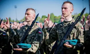 Żołnierze w mundurach polowych, z karabinami i beretami, składają przysięgę. To ważny moment ich zasadniczej służby wojskowej.