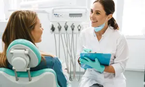 Uśmiechnięta dentystka omawia z pacjentką efekty leczenia aparatem ortodontycznym.