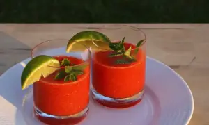 Två glas med frysta jordgubbsdrinkar, garnerade med lime och mynta. Perfekt för ett strawberry daiquiri recept.