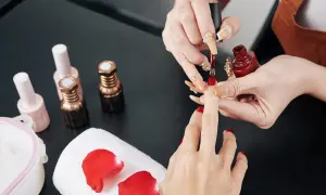 Manicure w trakcie. Stylistka nakłada czerwony lakier. Zastanawiasz się, jak przyspieszyć wysychanie lakieru do paznokci?