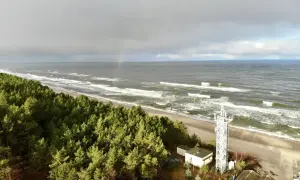Plaża Kąty Rybackie z wieżą widokową i lasem sosnowym. Na niebie tęcza.