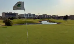 Bandera de Arcosur en un campo de golf, con edificios residenciales y grúas de construcción al fondo.