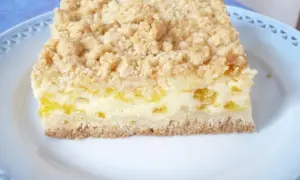 Ein Stück saftiger Mandarinenkuchen vom Blech mit Streuseln auf einem blauen Teller.