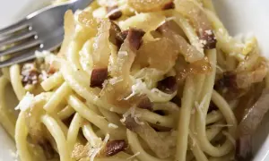 Ein Teller Pasta mit knusprigen Speckwürfeln, die zeigen, was ist Guanciale: luftgetrockneter Schweinebackenspeck, der für den authentischen Geschmack sorgt.