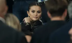 Selena Gomez w czarnej kurtce i bluzce w panterkę, z dłonią opartą o policzek. Fani spekulują o jej ciąży.
