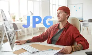 Mężczyzna w czapce i czerwonej koszuli pracuje przy komputerze, tworząc projekt graficzny. Duży napis JPG sugeruje, że pracuje nad plikiem graficznym.