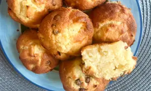 Saftige Apfelmus Muffins mit Schokostückchen auf einem blauen Teller. Einer ist aufgeschnitten und zeigt die lockere Textur.