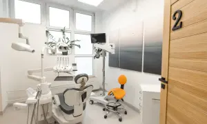 Nowoczesny gabinet stomatologiczny z fotelem dentystycznym, mikroskopem i drzwiami z numerem 2.