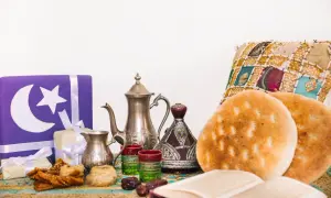 Przygotowania do iftaru: ozdobne prezenty, tradycyjny czajniczek, daktyle, pieczywo i książka.