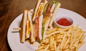 Idealne przekąski do piwa: chrupiące frytki i soczyste kanapki club sandwich z kurczakiem, bekonem i jajkiem.