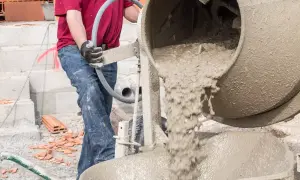 Robotnik miesza chudy beton, dbając o właściwe proporcje składników.