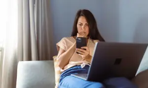Besorgte Frau am Handy, die über eine neue Betrugsmasche Immobilien recherchiert.