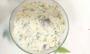 Pyszny przepis na śledzie w śmietanie z jabłkiem i ogórkiem, doprawione świeżym koprem. Idealna przekąska!