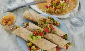 Leckere wraps vegetarisch gefüllt mit geröstetem Brokkoli, Tomaten und Salat. Dazu ein Dip und ein Glas Wasser.