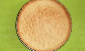 Upieczone ciasto na tartę słodką, lekko zarumienione, z widocznymi dziurkami, gotowe na pyszne nadzienie.