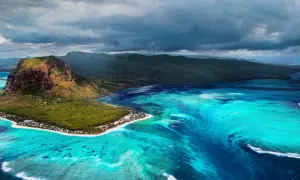 Podwodny wodospad w **Oceania** przy Le Morne Brabant, Mauritius. Turkusowa woda, góra i chmury.