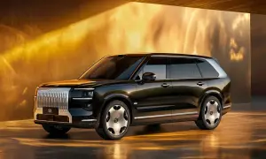 Elegancki, ciemny SUV Zeekr 9X z chromowanym grillem i futurystycznymi felgami, prezentowany w złotym, oświetlonym wnętrzu.