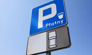 Znak D18 informuje o płatnym parkingu. Widoczny jest symbol samochodu, sugerujący miejsce parkingowe.