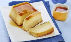 Un délicieux flan au lait concentré, parfait pour une recette flan lait concentré Nestlé. Servi sur une assiette blanche avec un coulis de caramel.