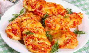 Delizioso petto di pollo alla pizzaiola, cotto al forno con pomodoro e formaggio filante, guarnito con aneto fresco.