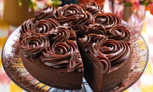 Una deliziosa torta al cioccolato, ricoperta da rosette di crema al cioccolato, con una fetta mancante che invita a un assaggio goloso.