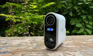 Une caméra de surveillance blanche avec une lumière bleue allumée, posée sur un banc en bois. Un moyen simple pour savoir si une caméra fonctionne.