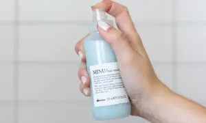 Mano che spruzza siero per capelli MINU. Scopri come si usa il siero per capelli per un colore luminoso e intenso.