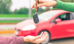 Passaggio di chiavi auto, un gesto che simboleggia cosa serve per vendere auto: fiducia e un nuovo inizio su quattro ruote rosse.