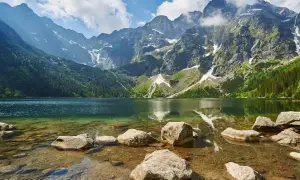 Piękna trasa nad Morskie Oko. Jezioro otoczone skalistymi szczytami Tatr, z zielonymi lasami i kamienistym brzegiem.