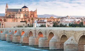 El Puente Romano cruza el Guadalquivir hacia la impresionante mezquita catedral de Córdoba, bañada por la luz del amanecer.