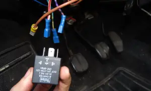 Main tenue, un relais Valeo pour clignotant fonctionne par intermittence. Des fils électriques sont connectés sous le tableau de bord.
