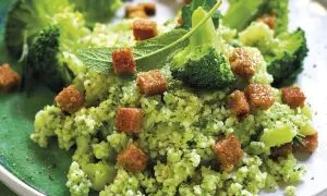 Un gustoso cous cous con broccoli, crostini dorati e foglie di menta fresca, un piatto colorato e salutare.