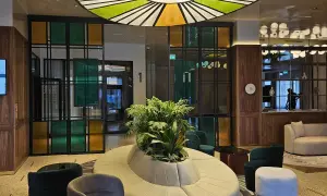 Nowoczesne wnętrze z designerską sofą i roślinnością. Kolorowe witraże i okrągły plafon tworzą niepowtarzalny klimat w grand hotelu Wrocław.