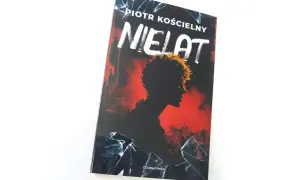 Okładka książki "Nielat" Piotra Kościelnego. Mroczna sylwetka postaci na tle czerwieni i pękniętego szkła.
