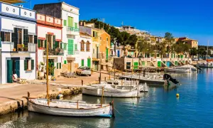 Bunte Häuserfront am Hafen, Boote im Wasser – ein idyllischer Urlaub auf Mallorca.