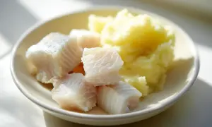 En tallrik med bitar av torsk bebis och potatismos.