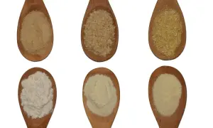 Sei cucchiai di legno mostrano diverse granulosità: dalla semola più fine al semolato più grossolano, per capire la differenza.