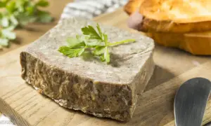 Un bloc de pâté rustique, garni de persil frais, prêt à être tartiné sur des toasts grillés. Un assaisonnement pâté parfait pour un apéritif gourmand.