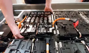 Manos trabajando en el interior de un paquete de baterías de coche eléctrico. Averiguar cuanto cuesta cambiar la bateria del coche es clave.