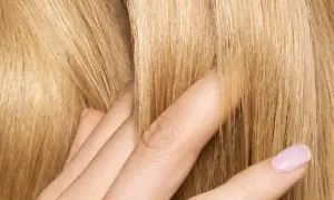 Dita accarezzano capelli biondi e setosi. Posso usare la maschera per capelli prima dello shampoo per ottenere questa morbidezza.