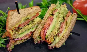 Tramezzini gusti freschi e colorati con avocado, pomodoro, cipolla rossa e insalata su pane integrale.