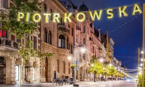 Ulica Piotrkowska nocą, iluminowana neonami i girlandami świateł. Idealne miejsce, by poczuć klimat Łodzi i zastanowić się, co zwiedzić w Łodzi.