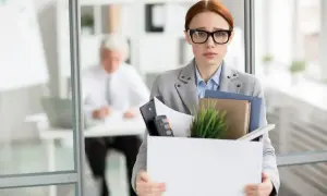 Smutna kobieta z pudełkiem rzeczy po likwidacji stanowiska pracy. Czy otrzyma należną odprawę?
