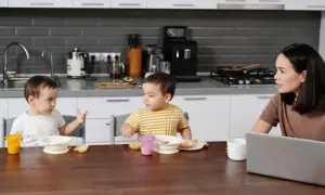 Mama słucha, kiedy dziecko zaczyna mówić, siedząc przy stole w kuchni.