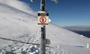 Zimowy szlak zamknięty na wielkim szyszaku. Tablica informuje o zakazie wstępu, a śnieg pokrywa wszystko wokół.